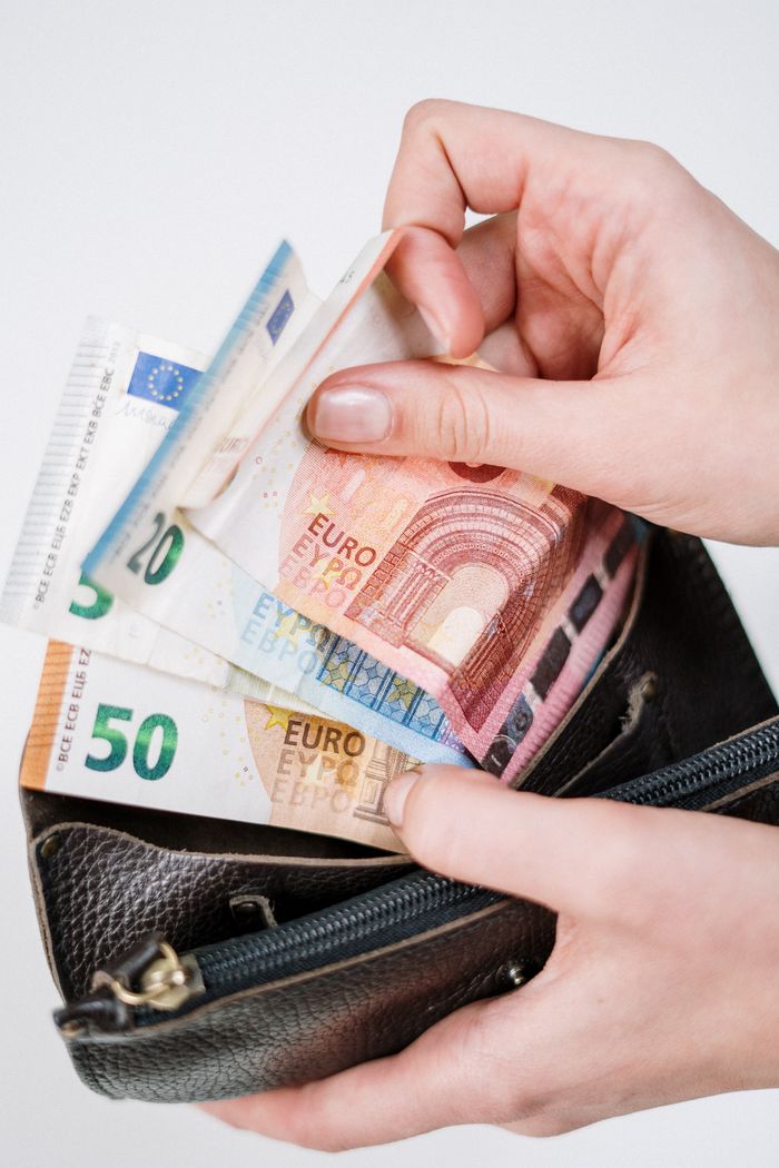 Close-up of hands counting euro banknotes from a leather wallet, representing financial transactions.